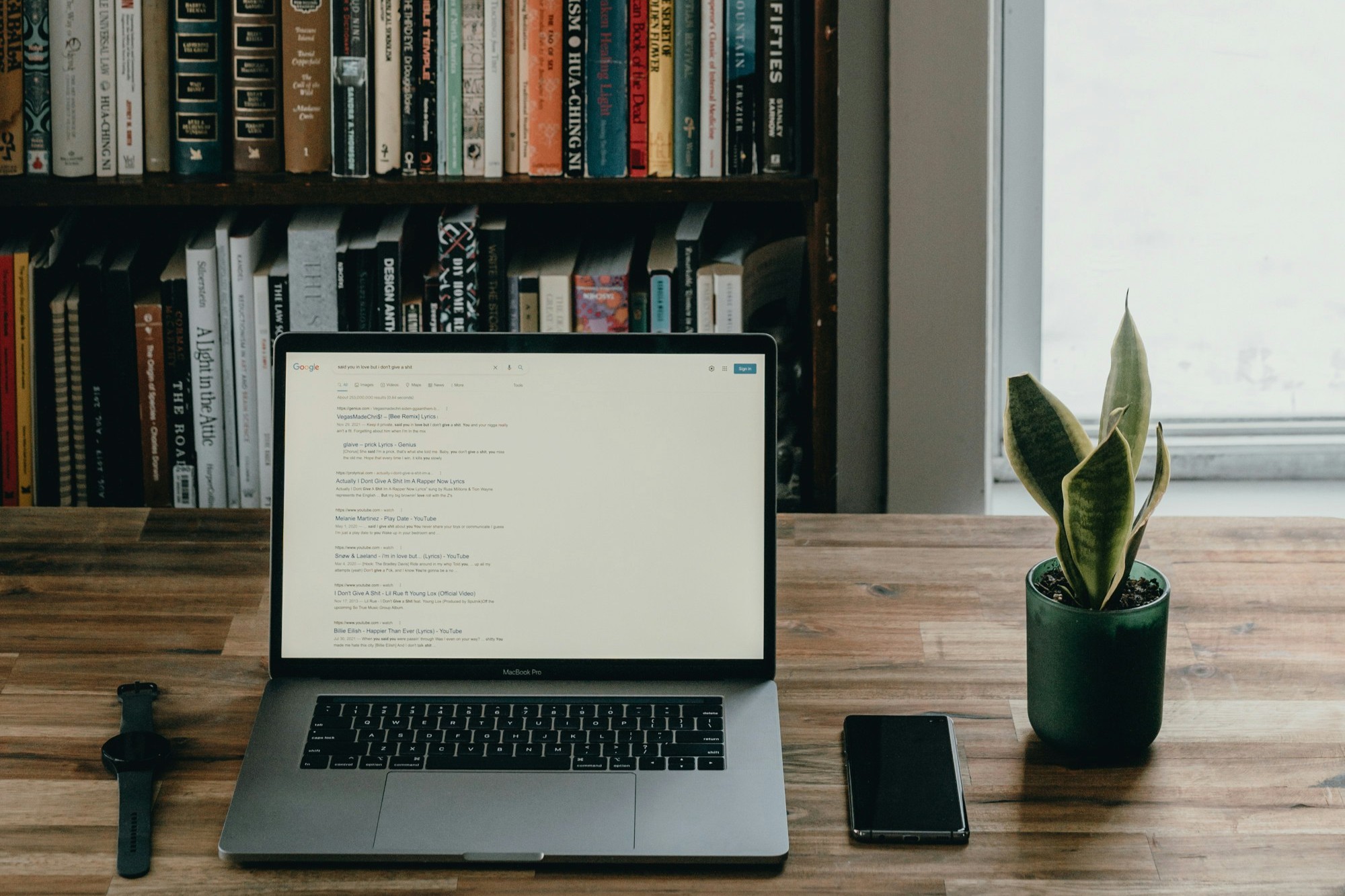 Computador aberto em frente a uma estante de livros
